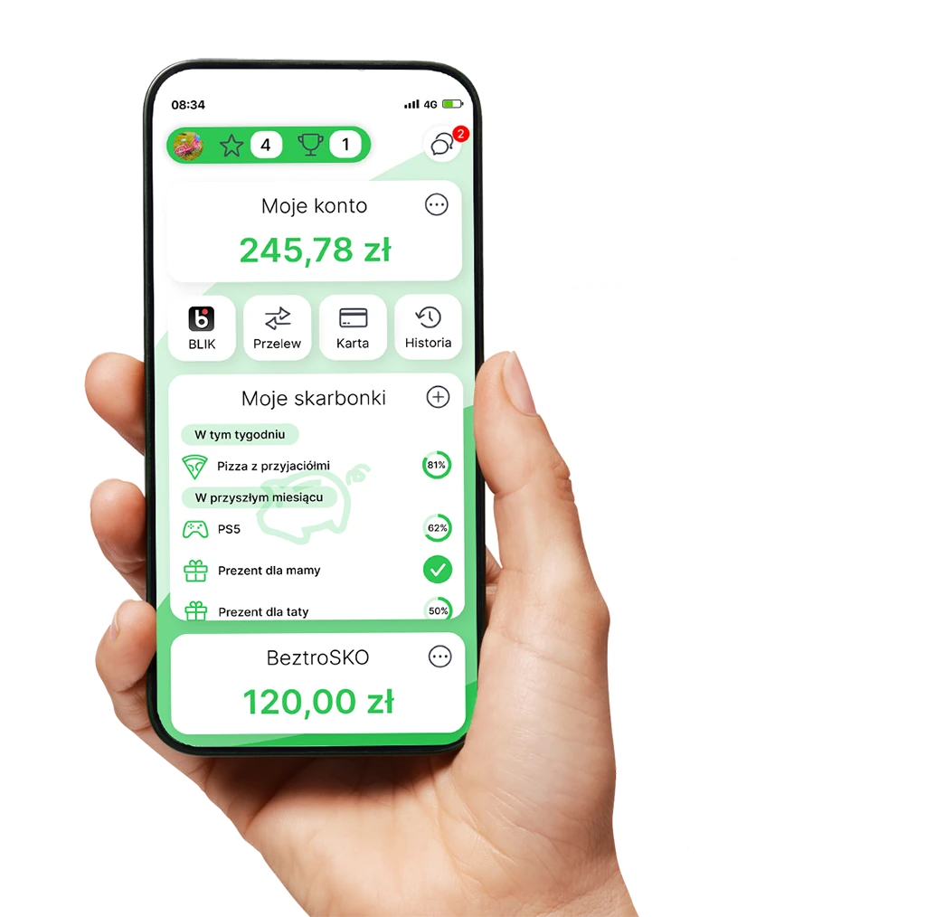 Dłoń trzymająca telefon z aplikacją Nasz Bank Junior. Na ekranie rachunek, skarbonki i cele oszczędzania.
